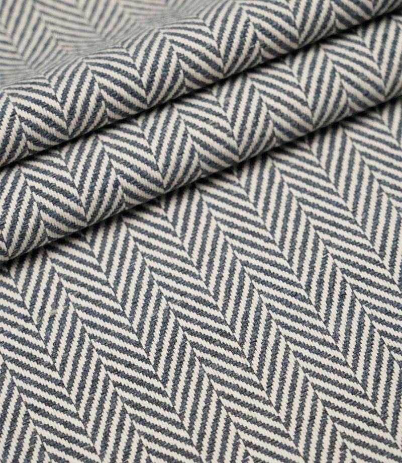Layered Bampton Ink woven fabric featuring a bold chevron herringbone design in ink blue and ivory, ideal for premium upholstery and home décor projects.