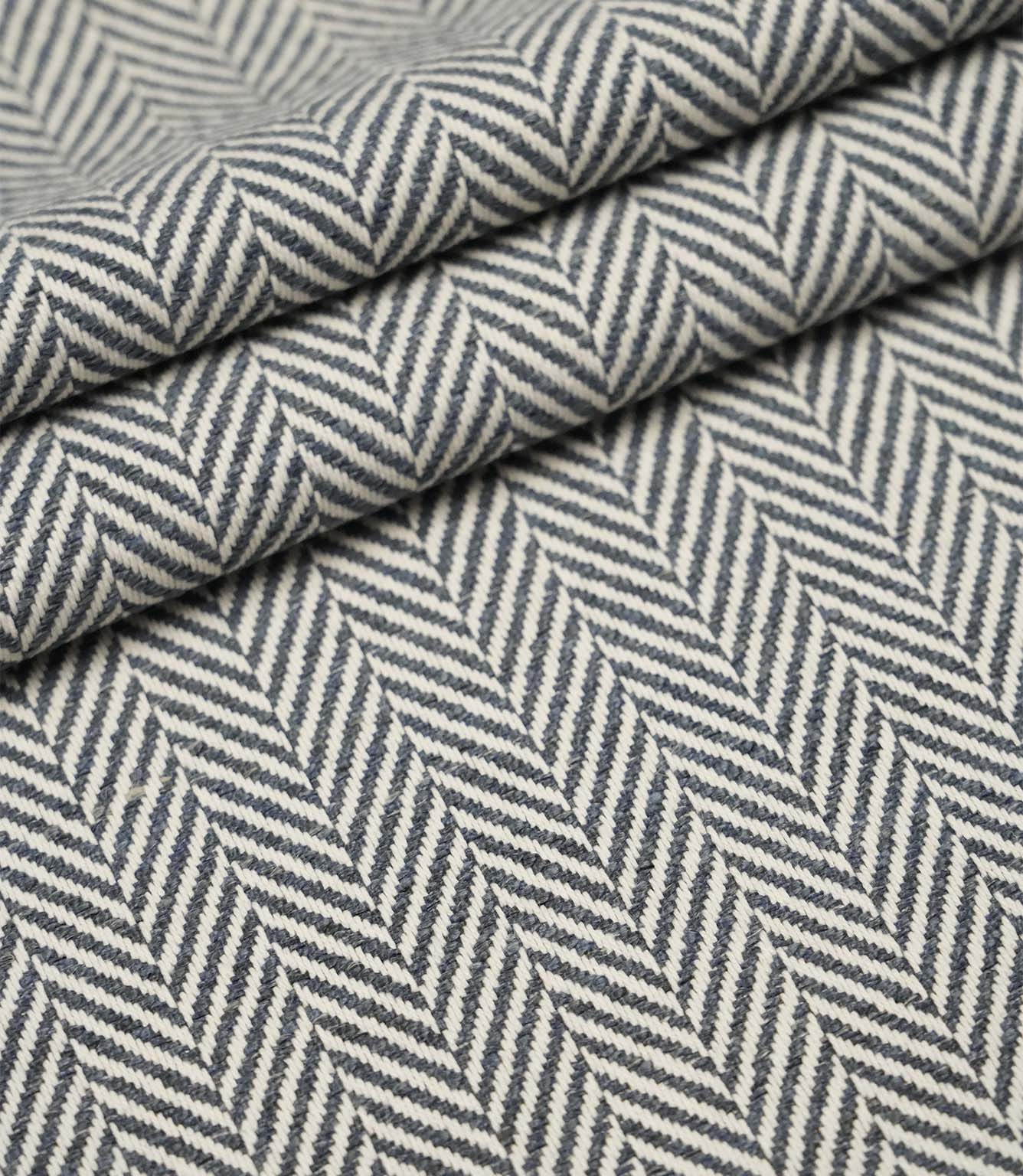 Layered Bampton Ink woven fabric featuring a bold chevron herringbone design in ink blue and ivory, ideal for premium upholstery and home décor projects.
