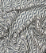 Draped Bampton Ink woven upholstery fabric displaying its soft drape, textured herringbone weave and striking ink blue and ivory chevron pattern.