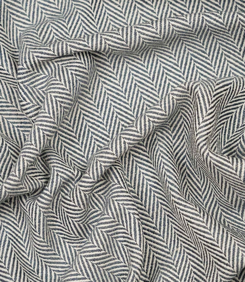 Draped Bampton Ink woven upholstery fabric displaying its soft drape, textured herringbone weave and striking ink blue and ivory chevron pattern.