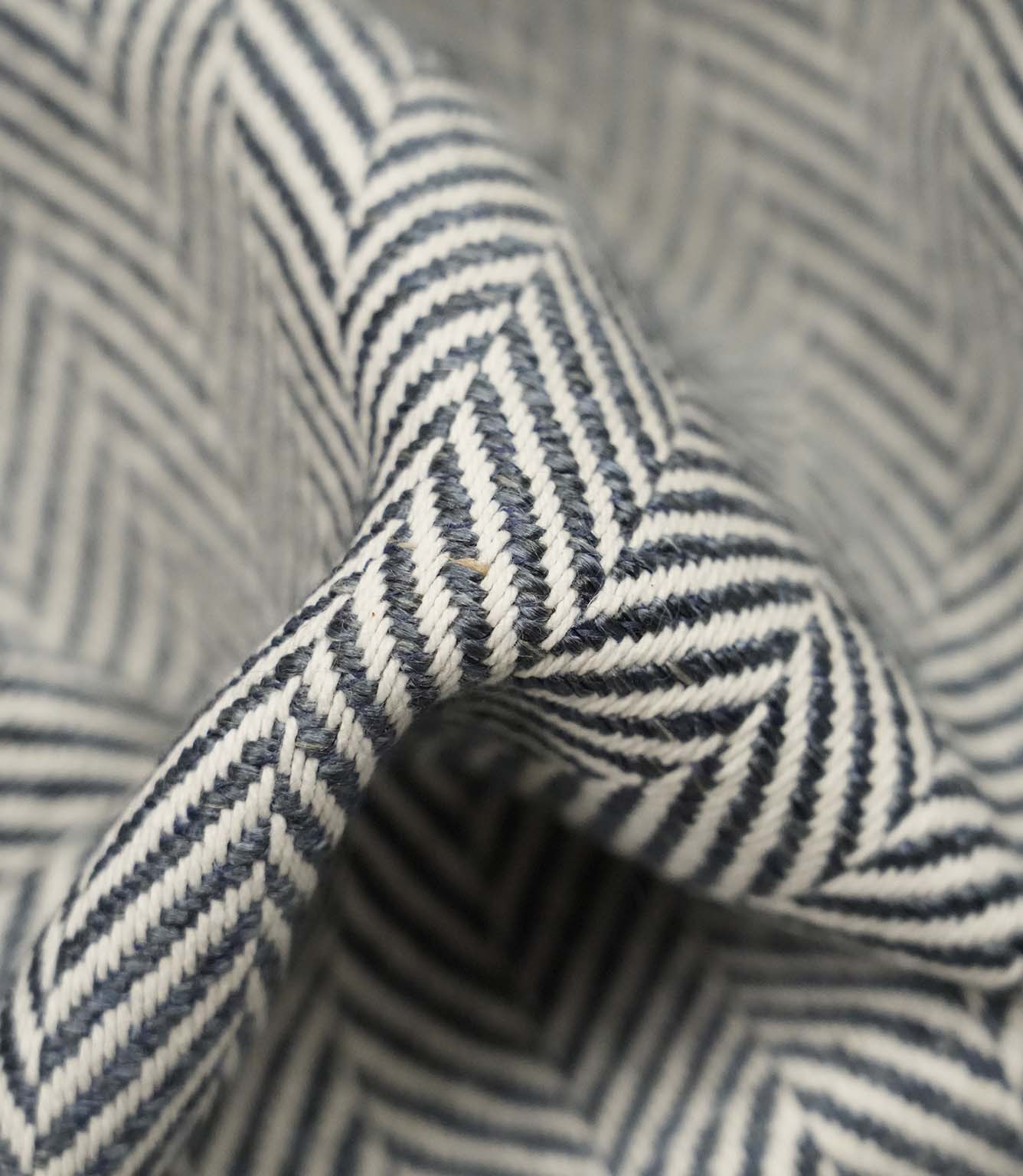 Macro close-up of Bampton Ink woven herringbone upholstery fabric highlighting the intricate chevron weave, rich texture and premium craftsmanship.