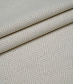 Layered folds of Bampton Jasmine upholstery fabric displaying the woven herringbone pattern and natural finish.