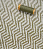 Bampton Matcha herringbone fabric with a matching green thread spool highlighting the woven texture and colour coordination.
