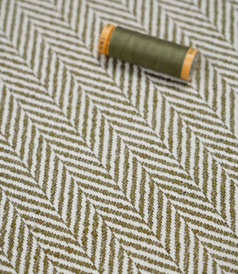 Bampton Matcha herringbone fabric with a matching green thread spool highlighting the woven texture and colour coordination.