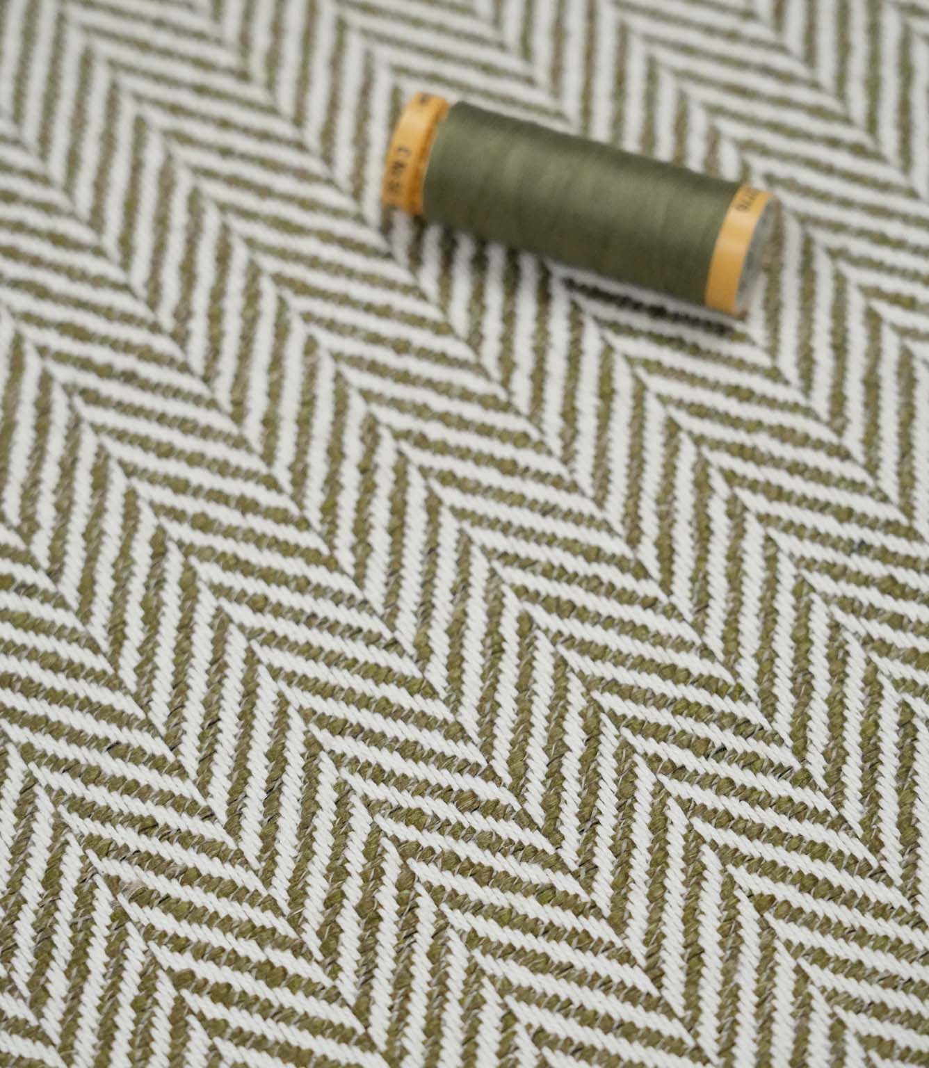 Bampton Matcha herringbone fabric with a matching green thread spool highlighting the woven texture and colour coordination.