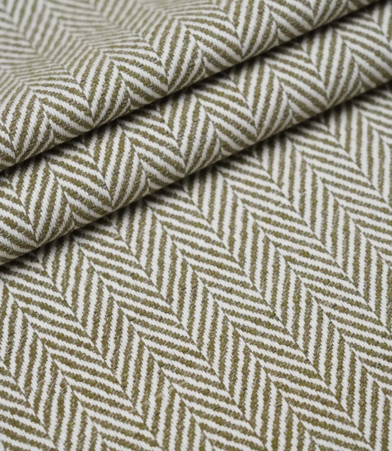 Layered folds of Bampton Matcha upholstery fabric displaying the textured woven herringbone pattern and fabric depth.