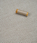 Bampton Taupe woven herringbone upholstery fabric with matching taupe sewing thread, highlighting the textured chevron weave for upholstery and soft furnishing projects.