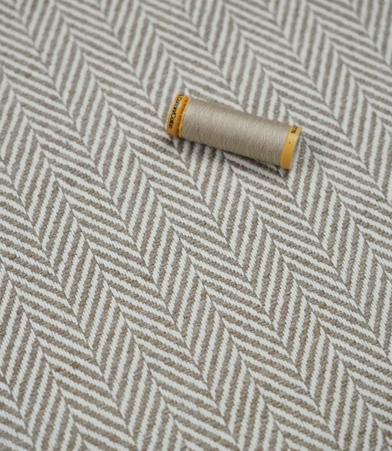 Bampton Taupe woven herringbone upholstery fabric with matching taupe sewing thread, highlighting the textured chevron weave for upholstery and soft furnishing projects.