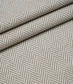 Layered Bampton Taupe woven fabric featuring a subtle chevron herringbone design in warm taupe and ivory, suitable for upholstery and home décor projects.