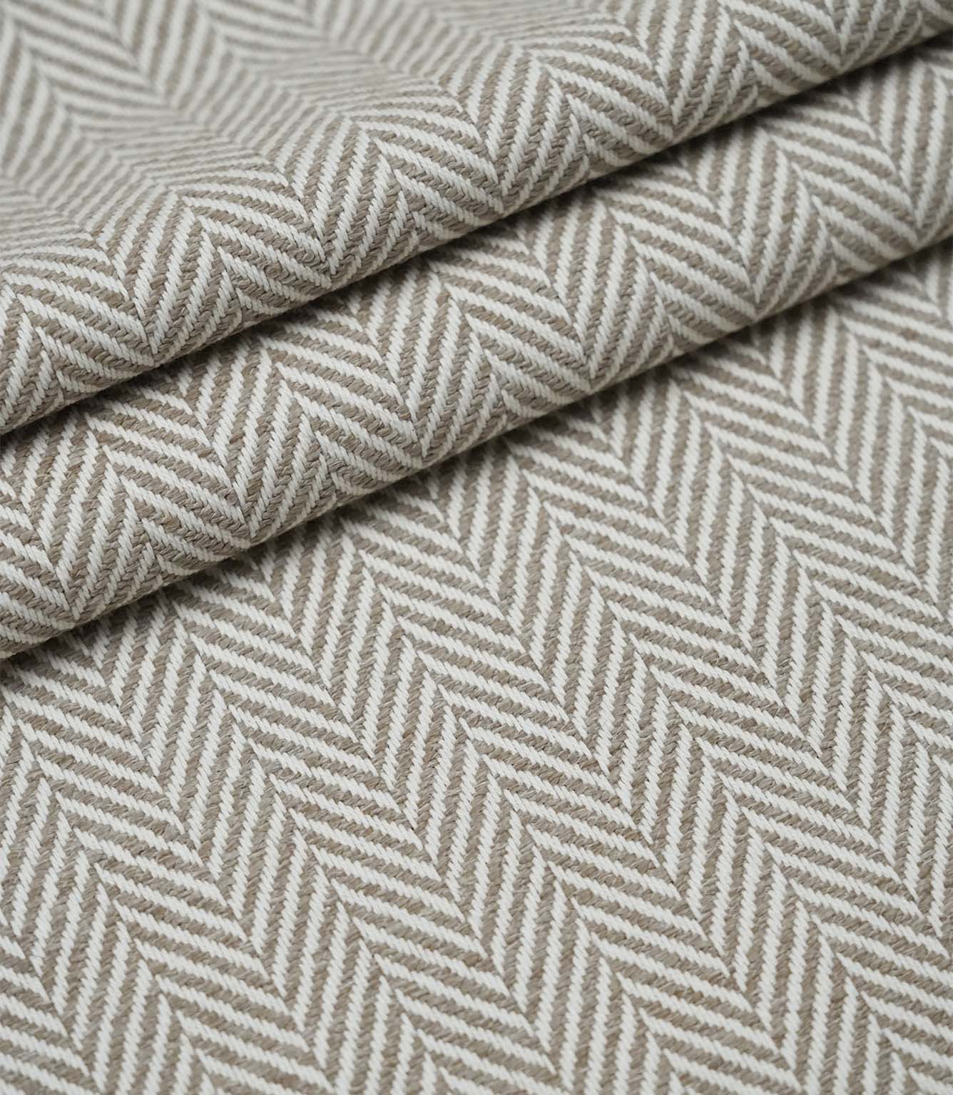 Layered Bampton Taupe woven fabric featuring a subtle chevron herringbone design in warm taupe and ivory, suitable for upholstery and home décor projects.