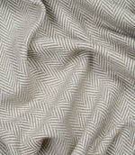 Draped Bampton Taupe woven upholstery fabric showcasing its soft drape, textured herringbone weave and elegant taupe and ivory chevron pattern.