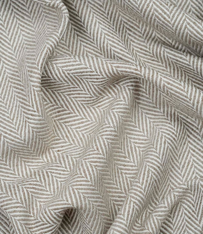Draped Bampton Taupe woven upholstery fabric showcasing its soft drape, textured herringbone weave and elegant taupe and ivory chevron pattern.