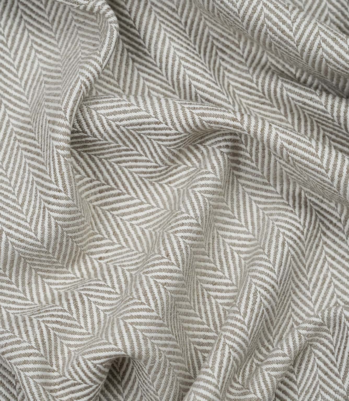 Draped Bampton Taupe woven upholstery fabric showcasing its soft drape, textured herringbone weave and elegant taupe and ivory chevron pattern.