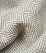 Macro close-up of Bampton Taupe woven herringbone upholstery fabric showing the intricate chevron weave, textured finish and premium craftsmanship.