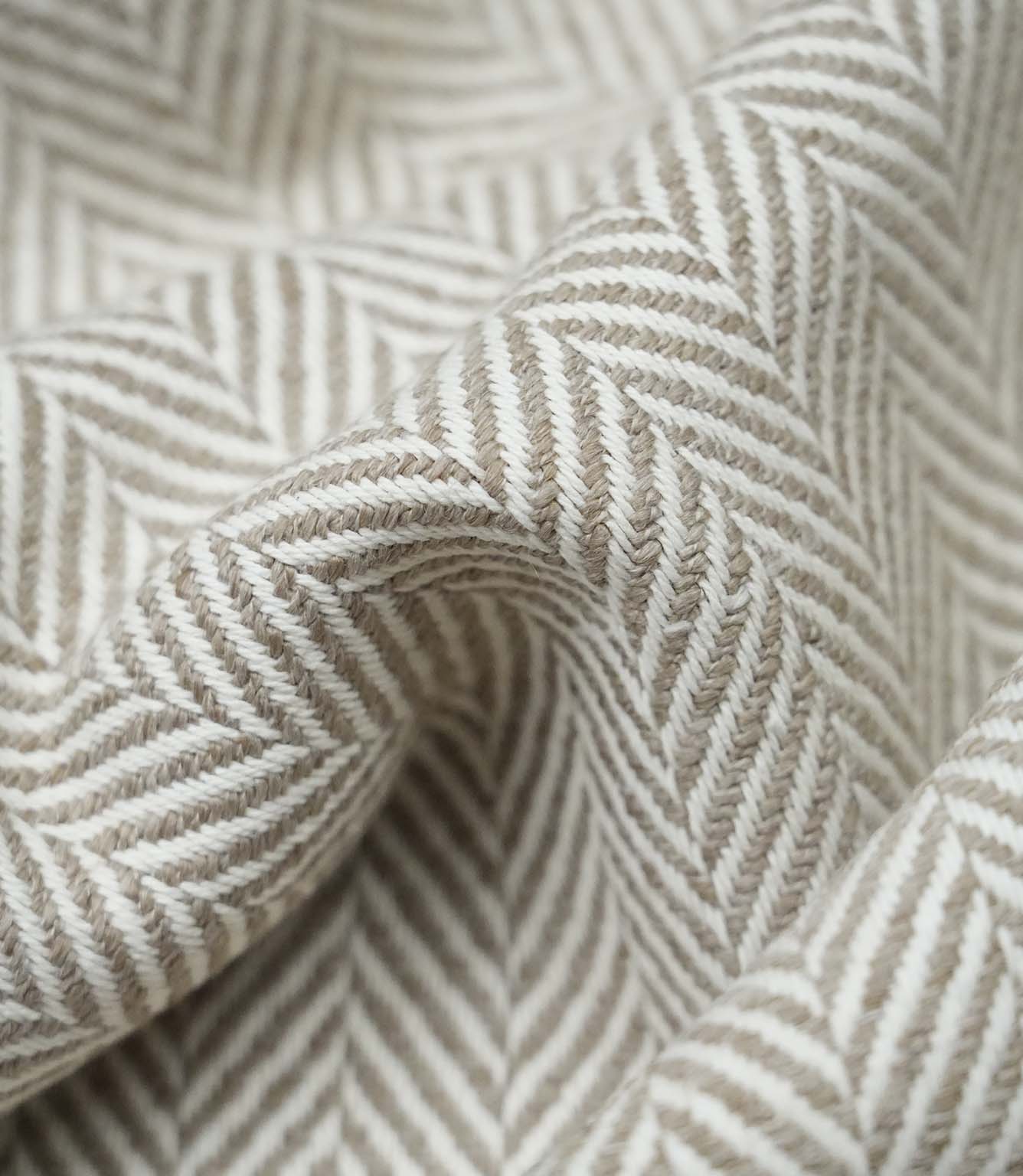 Macro close-up of Bampton Taupe woven herringbone upholstery fabric showing the intricate chevron weave, textured finish and premium craftsmanship.