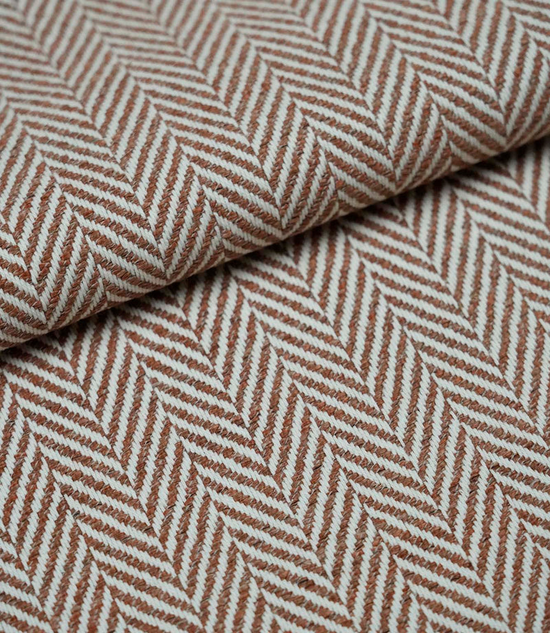 Folded Bampton Terracotta woven herringbone fabric showcasing its textured chevron weave, soft handle and durable upholstery weight for interior furnishing projects.
