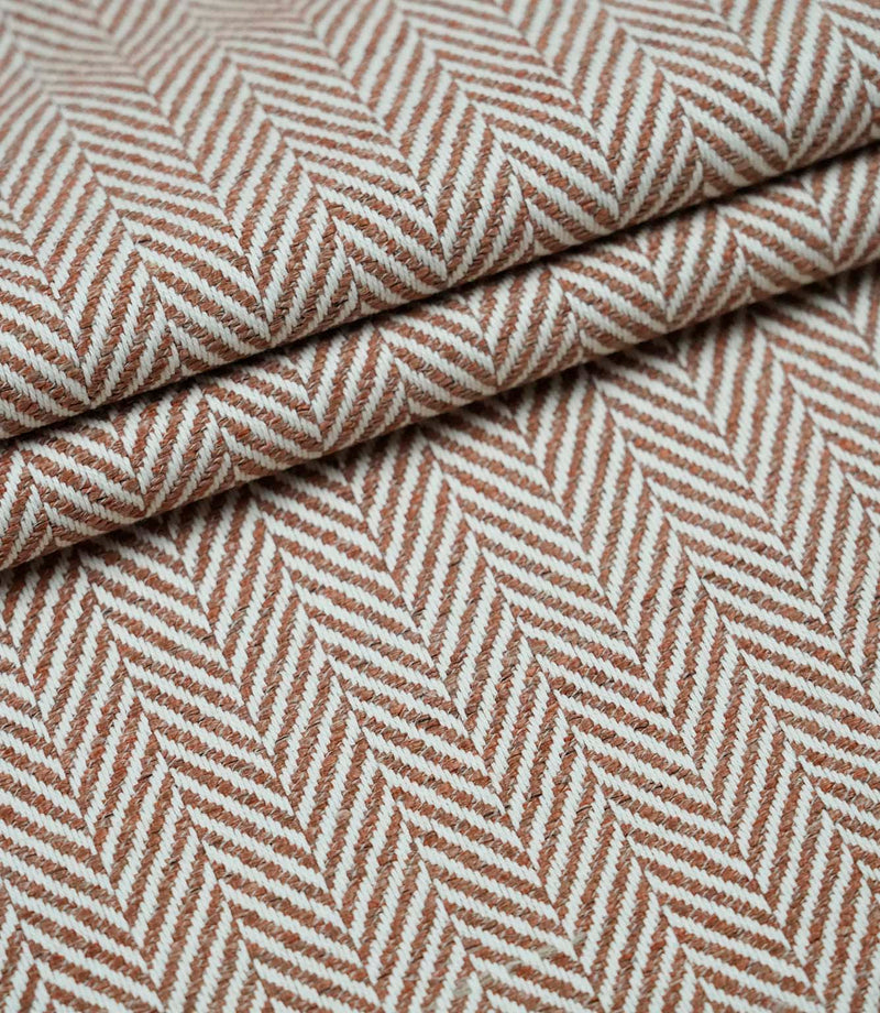 Layered Bampton Terracotta upholstery fabric displaying the repeating woven herringbone pattern, premium texture and versatile fabric suitable for cushions, curtains and upholstery.