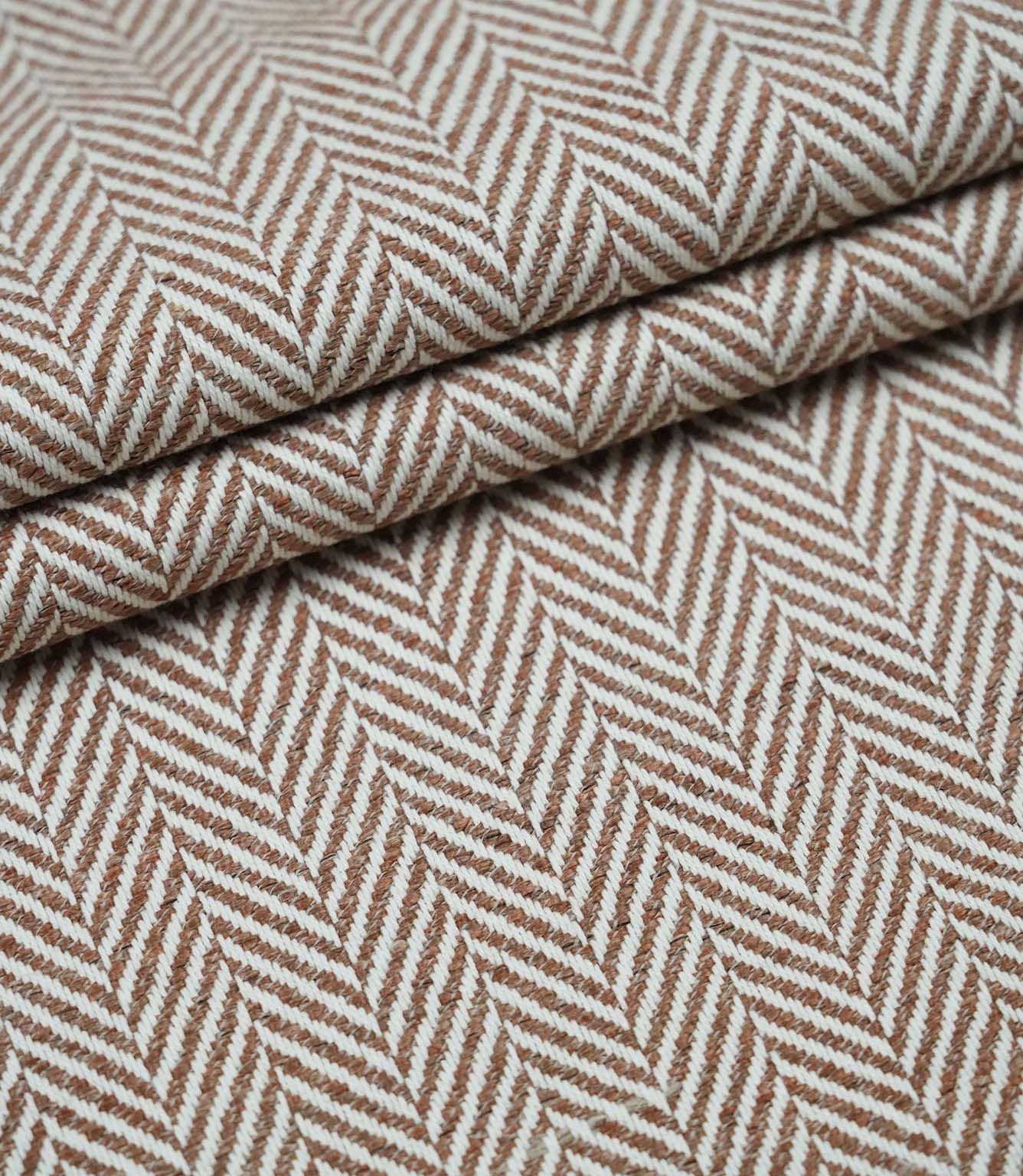 Layered Bampton Terracotta upholstery fabric displaying the repeating woven herringbone pattern, premium texture and versatile fabric suitable for cushions, curtains and upholstery.
