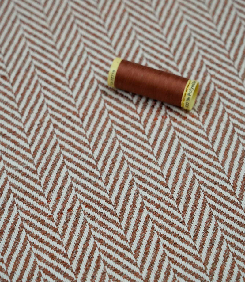 Bampton Terracotta herringbone upholstery fabric with matching terracotta sewing thread, highlighting the woven chevron design and coordinated colour for upholstery and sewing projects.