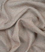 Draped Bampton Terracotta woven fabric showing the natural drape, textured herringbone weave and elegant terracotta and ivory chevron pattern for curtains and home décor.