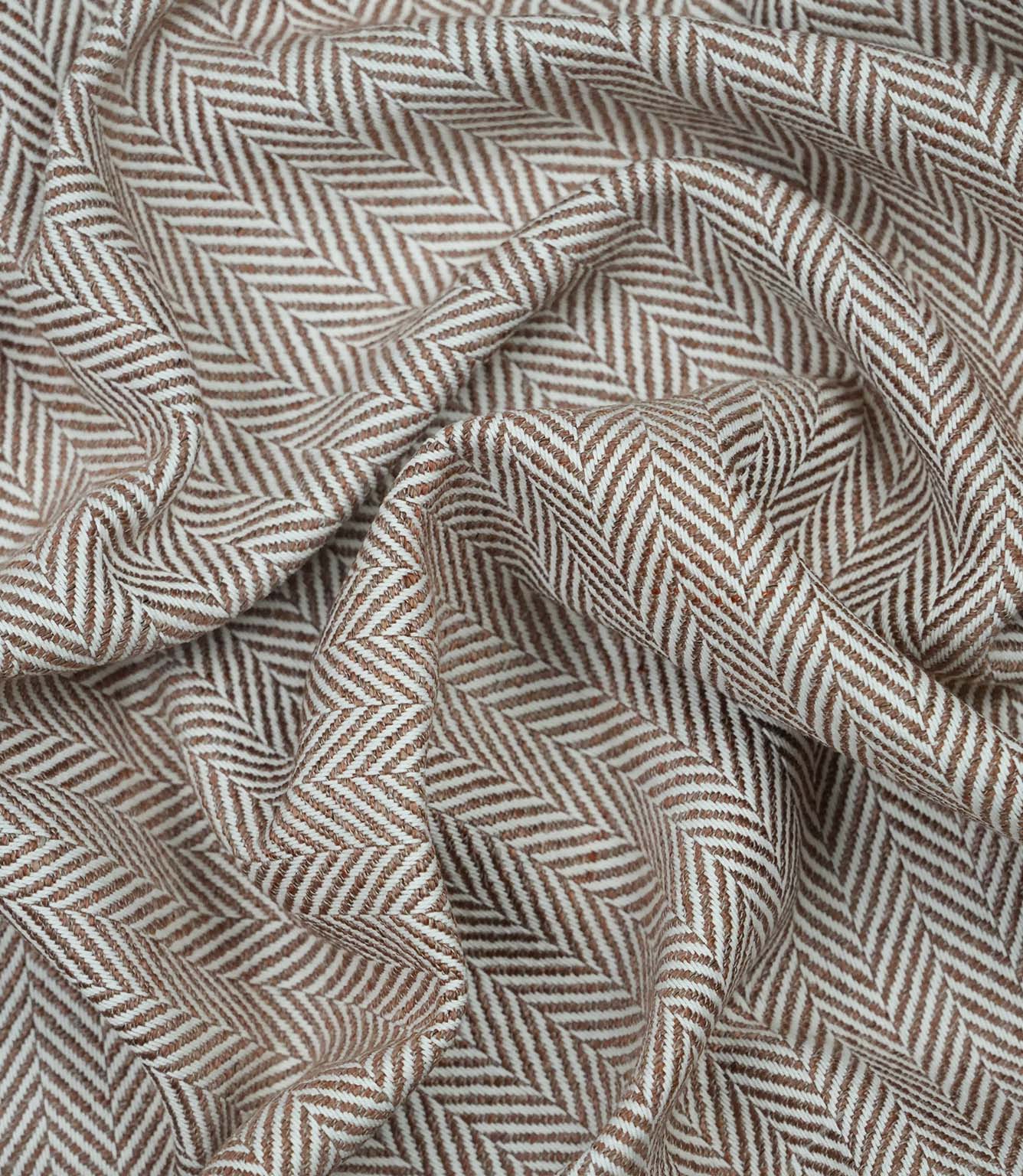 Draped Bampton Terracotta woven fabric showing the natural drape, textured herringbone weave and elegant terracotta and ivory chevron pattern for curtains and home décor.
