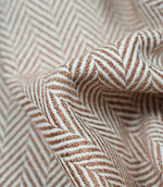 Detailed folded view of Bampton Terracotta herringbone upholstery fabric showing the depth of the woven chevron pattern, durable texture and soft finish for premium home furnishings.