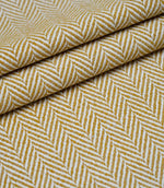 Layered folds of Bampton Turmeric upholstery fabric displaying the textured woven herringbone pattern and fabric depth.