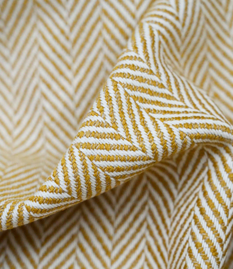 Close-up detail of Bampton Turmeric upholstery fabric highlighting the woven herringbone texture, fabric construction and premium finish.