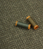 Bellmere Forest upholstery fire retardant fabric displayed with coordinating green and taupe sewing threads.