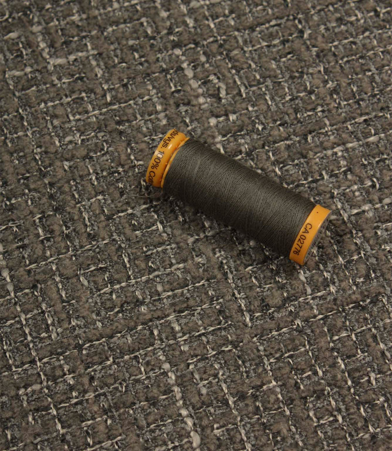Bellmere Slate upholstery fabric displayed with a coordinating dark grey sewing thread, showcasing the fabric's textured surface and woven construction.