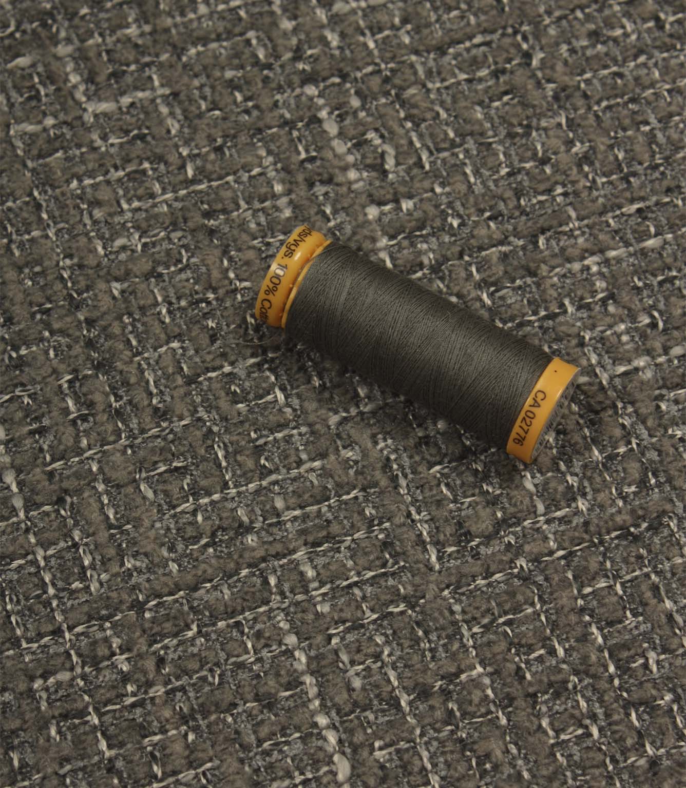 Bellmere Slate upholstery fabric displayed with a coordinating dark grey sewing thread, showcasing the fabric's textured surface and woven construction.