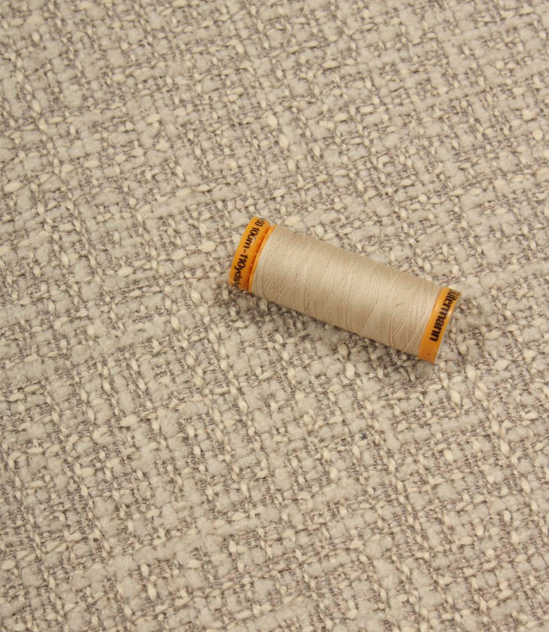 Bellmere Stone upholstery fabric displayed with a coordinating cream sewing thread, showcasing the fabric's textured surface and woven construction.