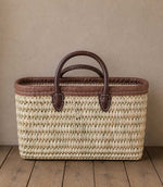 Woven basket tote bag with brown leather trim and handles