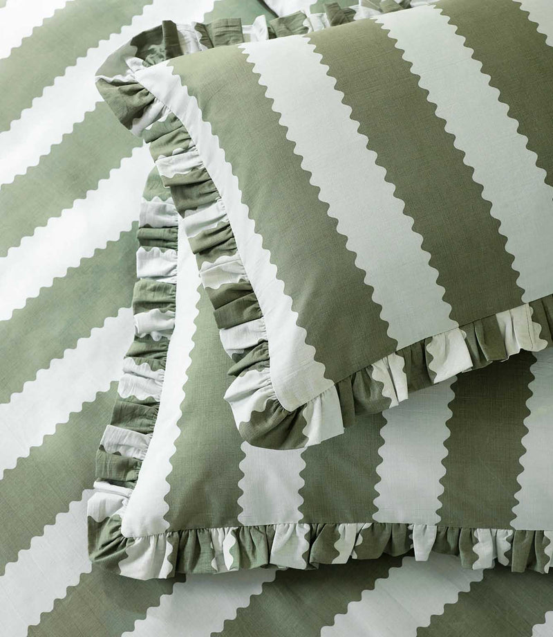 Detailed close-up of the Birdie Stripe Ruffle pillowcase and duvet cover in sage green and white, showing the wide scalloped stripe pattern, subtle woven texture and gathered ruffle trim.