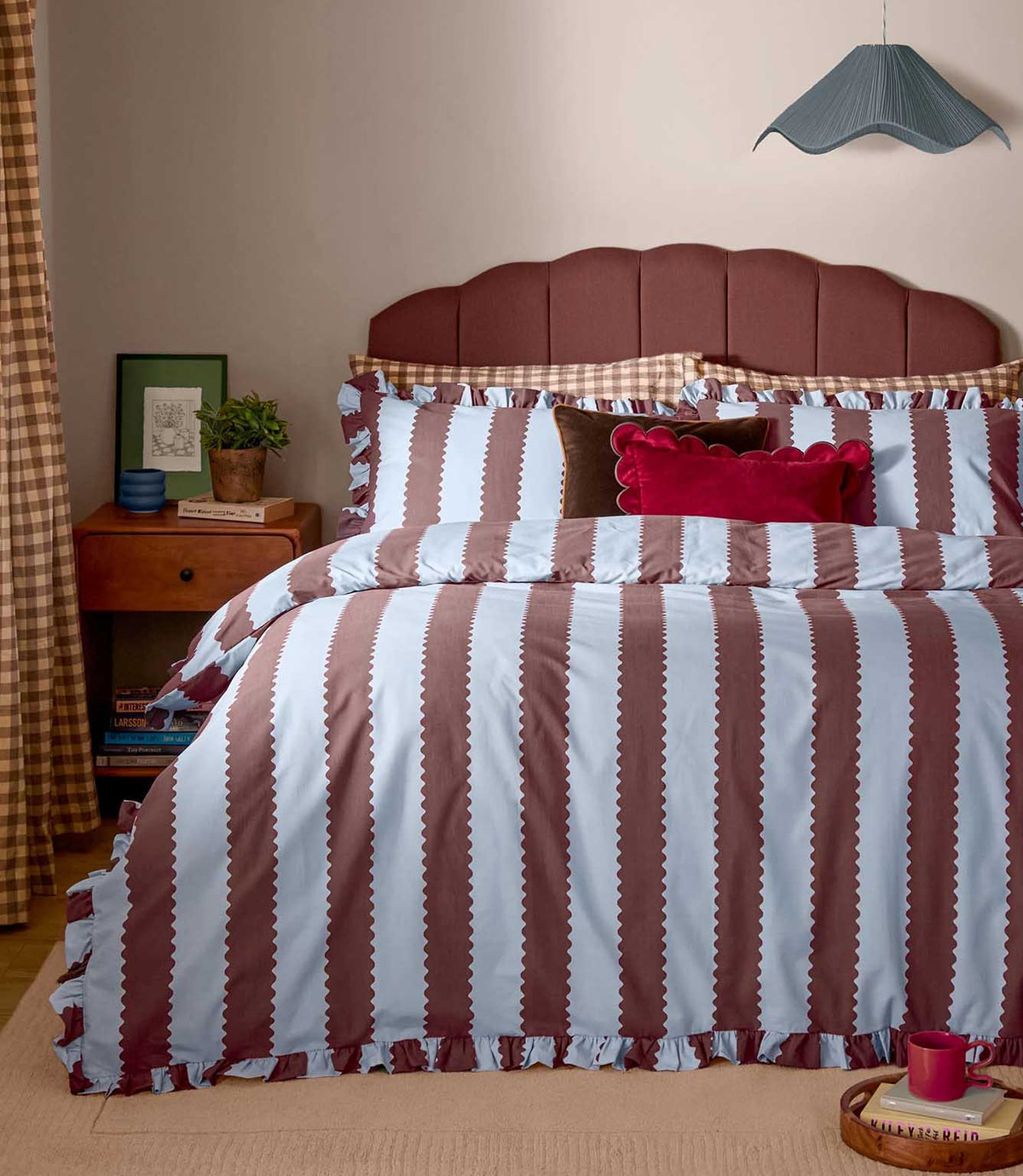 Birdie Stripe Ruffle duvet cover set in chocolate brown and pale blue, featuring wide scalloped vertical stripes and gathered ruffle edging, styled on a bed with coordinating pillows.