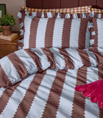 Close-up of the Birdie Stripe Ruffle bedding in chocolate brown and pale blue, showing the scalloped stripe design, soft fabric texture and gathered ruffle trim on the pillowcases.