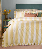 Birdie Stripe Ruffle duvet cover set in butter yellow and white, styled on a bed with matching striped ruffle pillowcases and layered cushions in a fresh, contemporary bedroom.