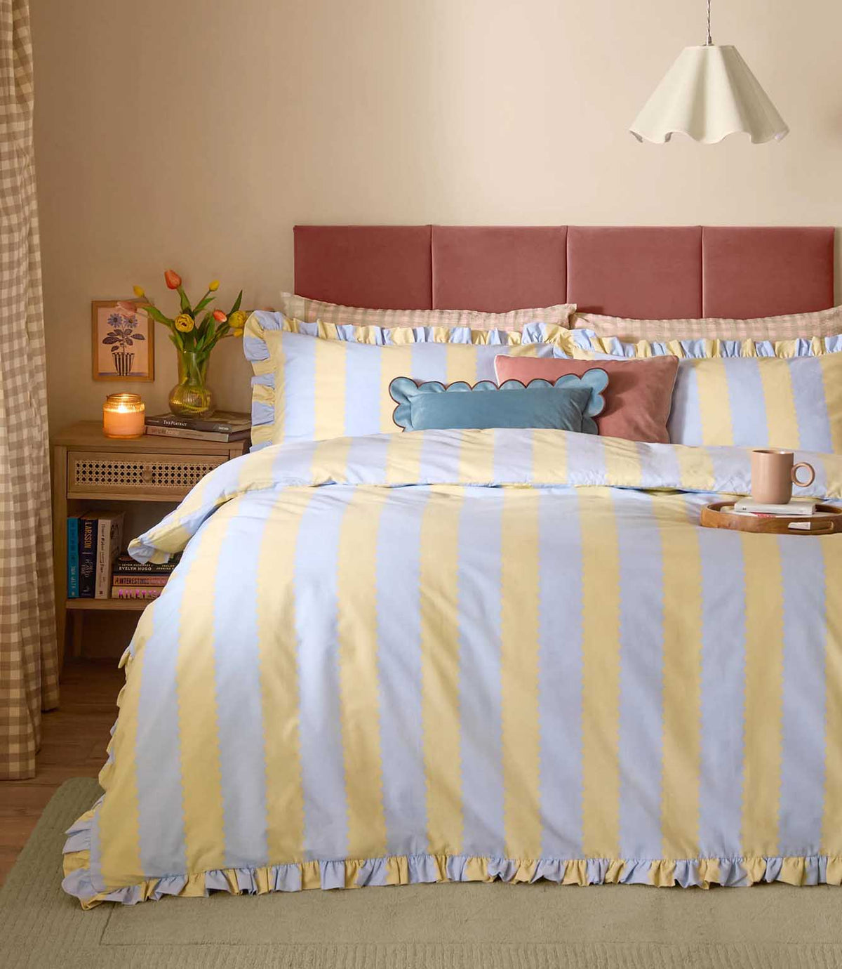 Birdie Stripe Ruffle duvet cover set in lemon yellow and sky blue, featuring wide scalloped vertical stripes and gathered ruffle edging, styled with matching pillowcases and layered cushions.