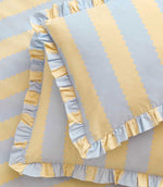 Detailed close-up of the Birdie Stripe Ruffle duvet cover and pillowcase in lemon yellow and sky blue, highlighting the scalloped stripe design, woven-look texture and gathered ruffle edging.