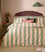 Birdie Stripe pink and green duvet cover set with scalloped vertical stripes and ruffled edging, styled with coordinating cushions in a colourful bedroom.