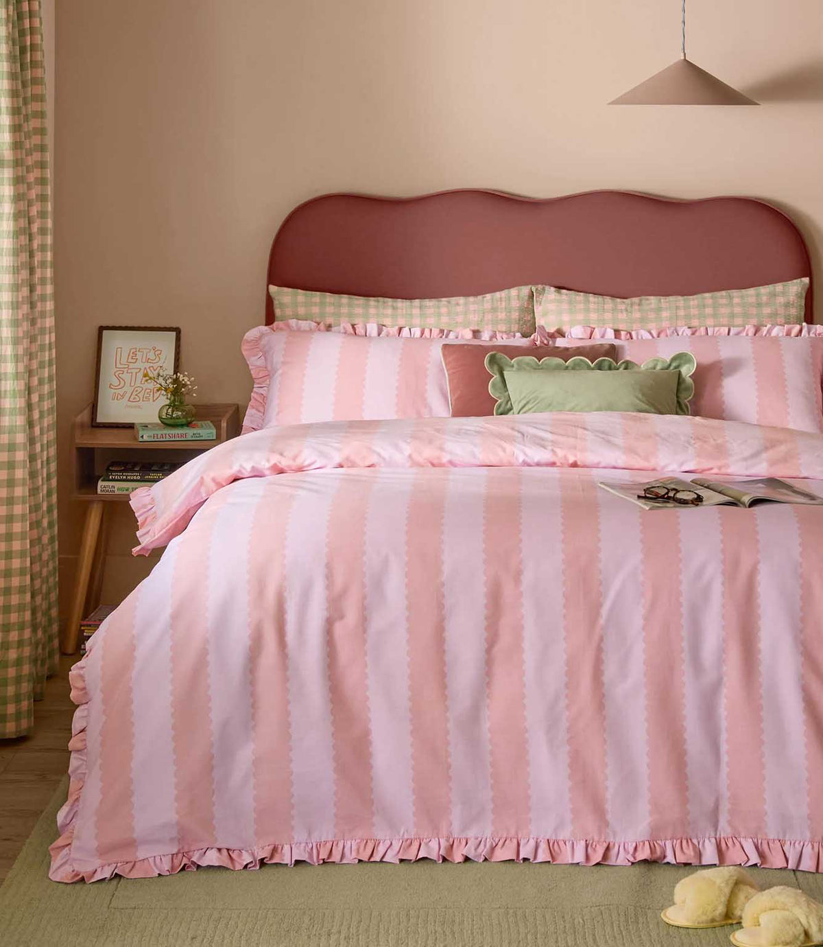 Birdie Stripe pink and raspberry duvet cover set with scalloped vertical stripes and ruffled edging, styled with coordinating cushions in a contemporary bedroom.