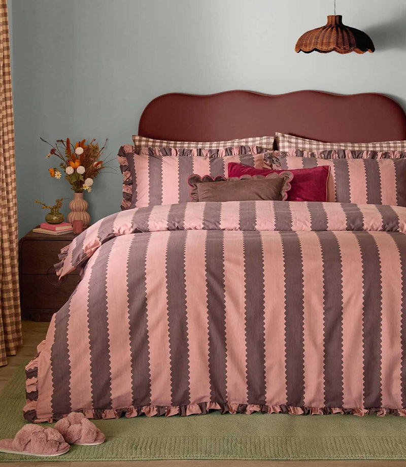 Birdie Stripe rose and chocolate duvet cover set with scalloped vertical stripes and ruffled edging, styled with coordinating cushions in a contemporary bedroom.