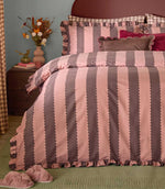 Birdie Stripe rose and chocolate duvet cover and matching ruffled pillowcases, styled with velvet cushions and floral accessories in a cosy bedroom.