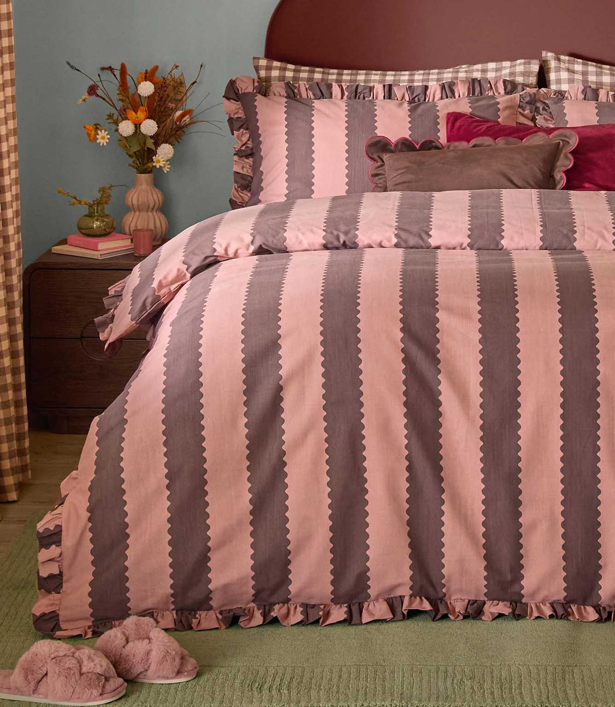 Birdie Stripe rose and chocolate duvet cover and matching ruffled pillowcases, styled with velvet cushions and floral accessories in a cosy bedroom.