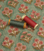 Floral patterned fabric with pink and green thread spools displayed for colour matching inspiration.