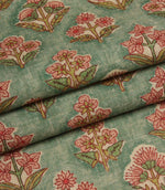 Folded botanical fabric in muted green and pink tones highlighting the soft woven texture.