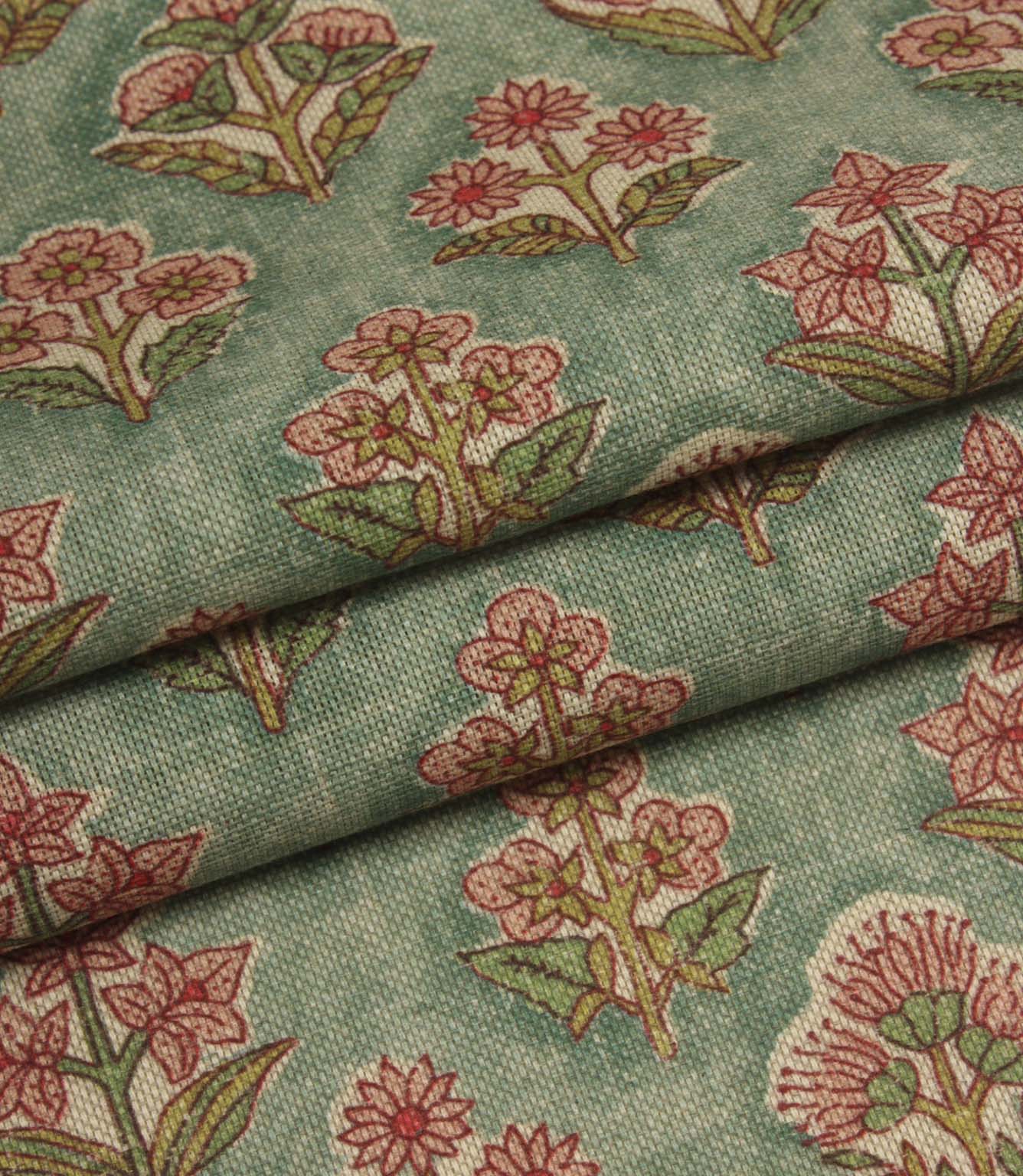 Folded botanical fabric in muted green and pink tones highlighting the soft woven texture.