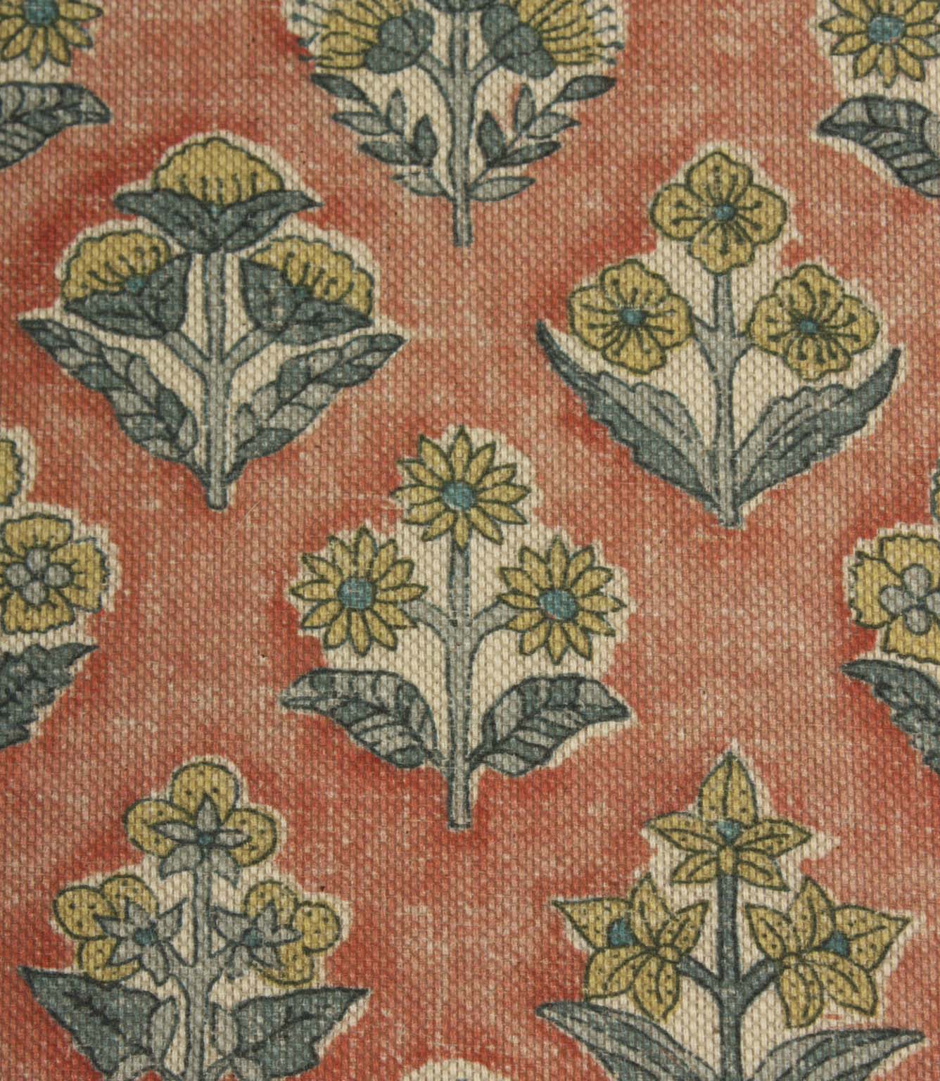 Close-up of Boho Blossom floral fabric showing detailed small-scale floral motifs in mustard yellow and slate blue on a textured terracotta woven base.