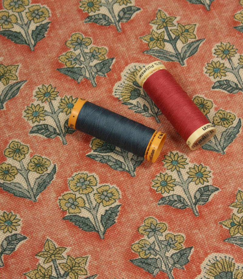 Boho Blossom floral fabric with coordinating navy and coral thread spools displayed on the terracotta ditsy floral pattern.