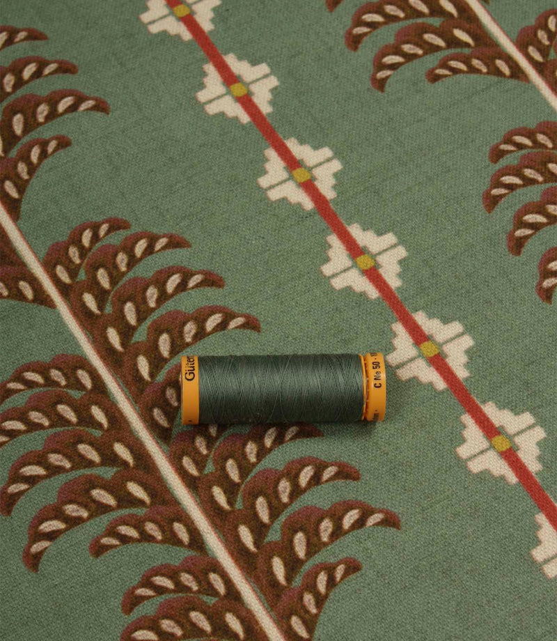 Boho Trail Mineral upholstery and curtain fabric displayed with coordinating green thread, highlighting the botanical motif and heritage-inspired design.